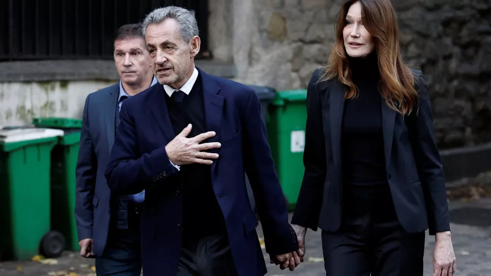 Former French President Nicolas Sarkozy leaves his house with his wife Carla Bruni-Sarkozy on the day of his incarceration at the Sante prison to begin his five-year prison sentence for criminal conspiracy over attempts to raise campaign funds from Libya, in Paris, France, October 21, 2025. REUTERS/Benoit Tessier