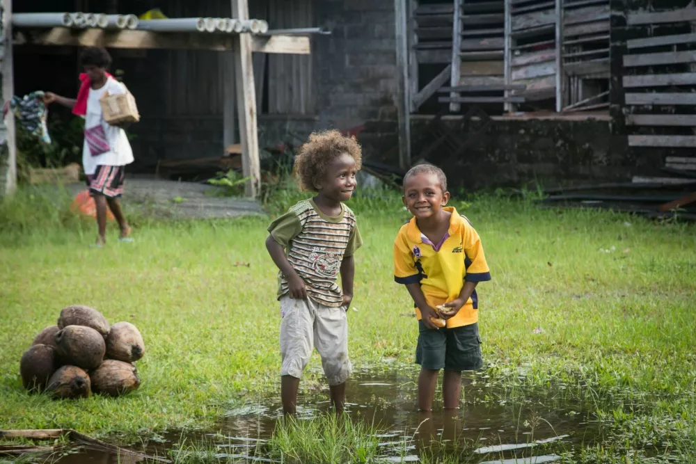 Batuna, Solomon Islands - May 28, 2015: Two boys are playing in a puddle of water at the local market in Batuna village. / Foto: Olli0815