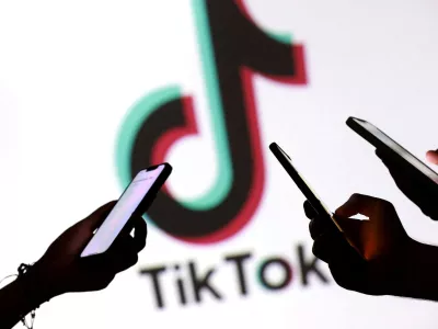 FILE PHOTO: Teenagers pose for a photo while holding smartphones in front of a TikTok logo in this illustration taken September 11, 2025. REUTERS/Dado Ruvic/Illustration/File Photo