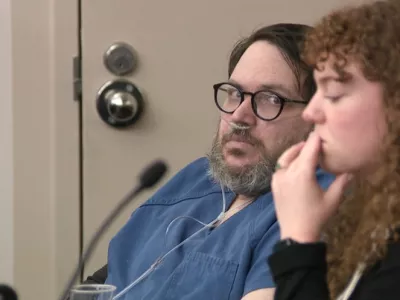 In this image captured from video, Nicholas Rossi, left, appears in a Salt Lake City court, Monday, Oct. 20, 2025, for his sentencing hearing on a rape conviction. To his right is MacKenzie Potter of the Salt Lake Legal Defender Association. (Fox 13/Pool Video via AP)