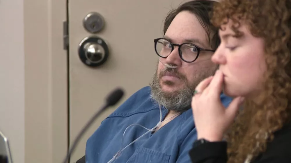 In this image captured from video, Nicholas Rossi, left, appears in a Salt Lake City court, Monday, Oct. 20, 2025, for his sentencing hearing on a rape conviction. To his right is MacKenzie Potter of the Salt Lake Legal Defender Association. (Fox 13/Pool Video via AP)