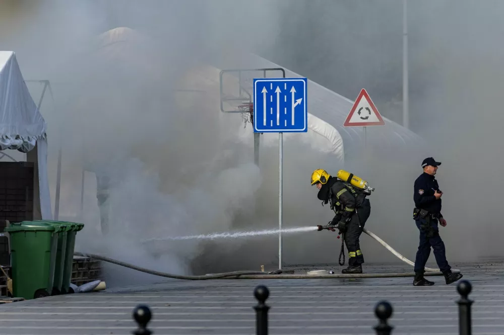 A firefighter works as smoke rises from a burning tent following an incident in front of the Parliament in Belgrade, Serbia, October 22, 2025. REUTERS/Djordje Kojadinovic