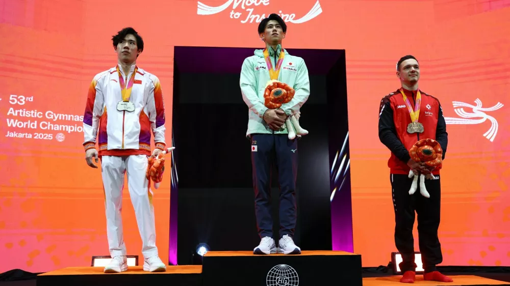Artistic Gymnastics - 2025 World Artistic Gymnastics Championships - Mens Artistic Gymnastics - All-Around Final - Indonesia Arena, Jakarta, Indonesia - October 22, 2025 Gold medallist Japan's Daiki Hashimoto celebrates on the podium after winning the All-Around Final with silver medallist China's Zhang Boheng and bronze medallist Switzerland's Noe Seifert REUTERS/Issei Kato