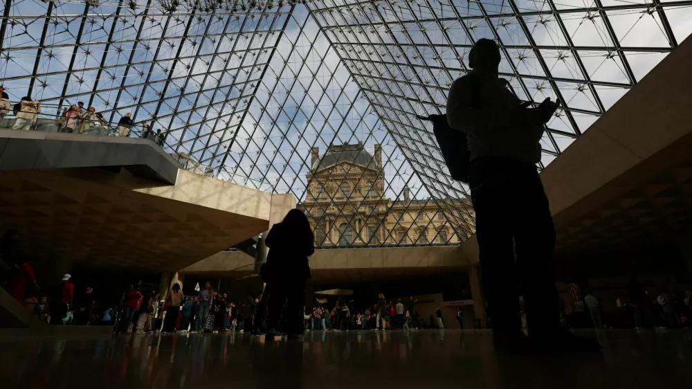 Visitors walk below the glass Pyramid at the Louvre Museum on the day it reopened to the public for the first time since last Sunday's heist, while the Galerie d'Apollon where eight pieces of Napoleon and the Empress's jewelry collection displayed in the gallery were stolen by thieves, remains closed, in Paris, France, October 22, 2025. REUTERS/Gonzalo Fuentes