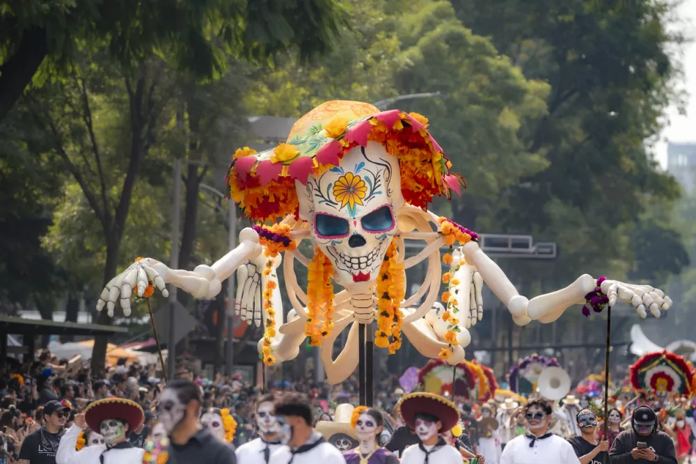 Mexico City, Mexico - November 2, 2024: A massive skeleton float adorned with flowers and traditional decorations parades through Mexico City, celebrating the vibrant Day of the Dead festival.