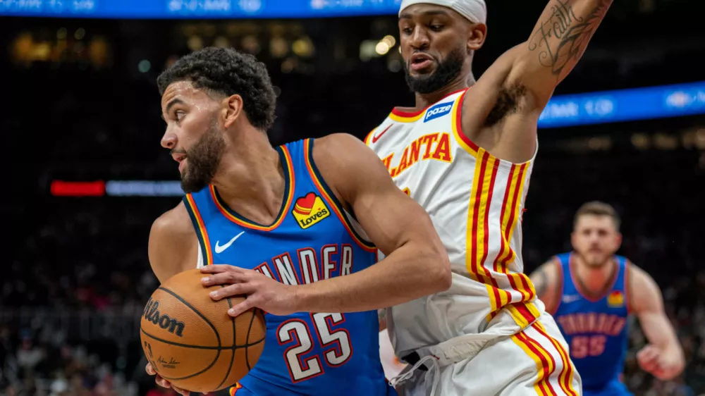 Oklahoma City Thunder guard Ajay Mitchell (25), left, drives the ball against Atlanta Hawks guard Nickeil Alexander-Walker during the first half of an NBA basketball game, Saturday, Oct. 25, 2025, in Atlanta. (AP Photo/Erik Rank)