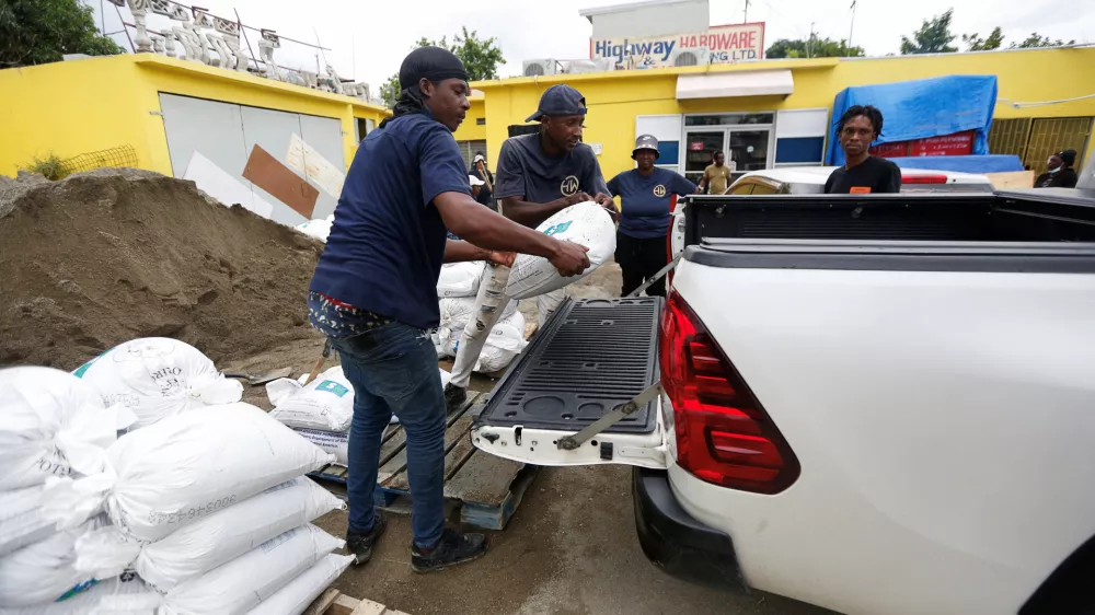 People load a sandbag onto a vehicle, in preparation for the arrival of Hurricane Melissa, in the Harbour View neighbourhood of Kingston, Jamaica, October 25, 2025. REUTERS/Octavio Jones