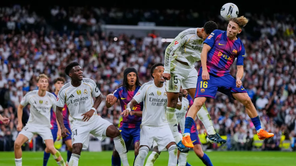 Barcelona's Fermin Lopez, top right, goes for a header with Real Madrid's Jude Bellingham during the Spanish La Liga soccer match between Real Madrid and Barcelona, in Madrid, Sunday, Oct. 26, 2025. (AP Photo/Manu Fernandez)