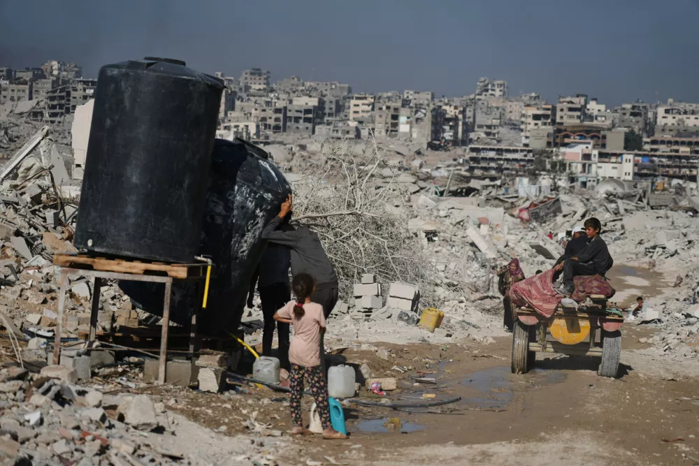 Palestinians collect water amid the ruins of Gaza City, Sunday, Oct. 26, 2025. (AP Photo/Jehad Alshrafi)