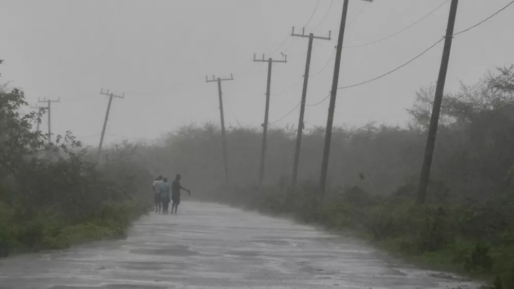 People walk along a road during the passing of Hurricane Melissa in Rocky Point, Jamaica, Tuesday, Oct. 28, 2025. (AP Photo/Matias Delacroix)