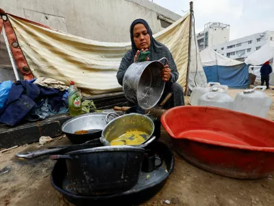 A displaced Palestinian woman washes kitchen items outside her tent, amid a ceasefire between Israel and Hamas, in Gaza City, November 4, 2025. REUTERS/Mahmoud Issa