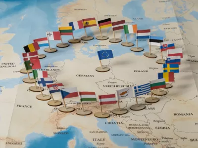 colorful flags of european union member countries arranged in a symbolic circle on a detailed political map of europe / Foto: Alina Vytiuk