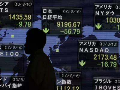 A pedestrian is silhouetted in front of an electronic board displaying stock price index of Japan (C) and other countries outside a brokerage in Tokyo August 16, 2010. The yen rose broadly on Monday as high-yielding currencies and Asian equities faltered, with talk of possible demand from Japanese exporters and investor fund repatriation also giving the yen a boost. REUTERS/Yuriko Nakao (JAPAN - Tags: BUSINESS EMPLOYMENT)