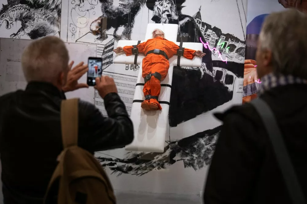 People take pictures of an art piece by British artist Mason Storm called "Saint or Sinner", depicting US President Donald Trump dressed in an orange prison jumpsuit on a cross, displayed at an gallery in Basel on November 3, 2025.,Image: 1050055687, License: Rights-managed, Restrictions: RESTRICTED TO EDITORIAL USE - MANDATORY MENTION OF THE ARTIST UPON PUBLICATION - TO ILLUSTRATE THE EVENT AS SPECIFIED IN THE CAPTION, Model Release: no