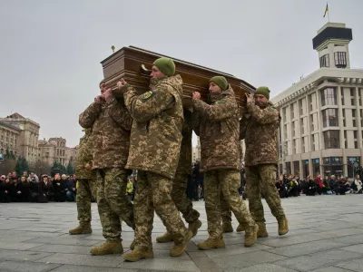 People kneel down as Ukrainian servicemen carry the coffin of their fellow-soldier and a well-known documentary photographer Kostiantyn Huzenko, 28, who was killed in Russia-Ukraine war, during the funeral ceremony in the Independence square in Kyiv, Ukraine, Friday, Nov. 7, 2025. (AP Photo/Efrem Lukatsky)