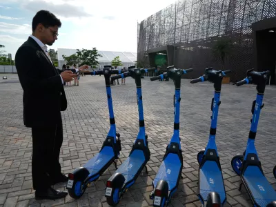 A person stands near electric scooters outside the venue of the COP30 U.N. Climate Summit, Saturday, Nov. 8, 2025, in Belem, Brazil. (AP Photo/Fernando Llano)