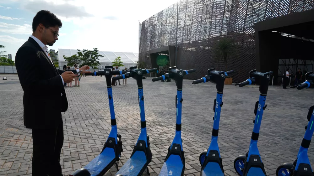 A person stands near electric scooters outside the venue of the COP30 U.N. Climate Summit, Saturday, Nov. 8, 2025, in Belem, Brazil. (AP Photo/Fernando Llano)