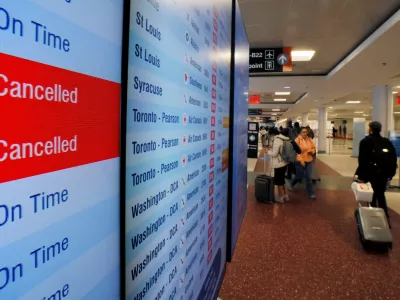 A board shows two cancelled American Airlines flights and three on time, as airlines cancelled flights at 40 major airports after the government imposed an unprecedented cut to air travel, citing air traffic control safety concerns because of a record-setting government shutdown, at Logan International Airport in Boston, Massachusetts, U.S., November 7, 2025.  REUTERS/Brian Snyder