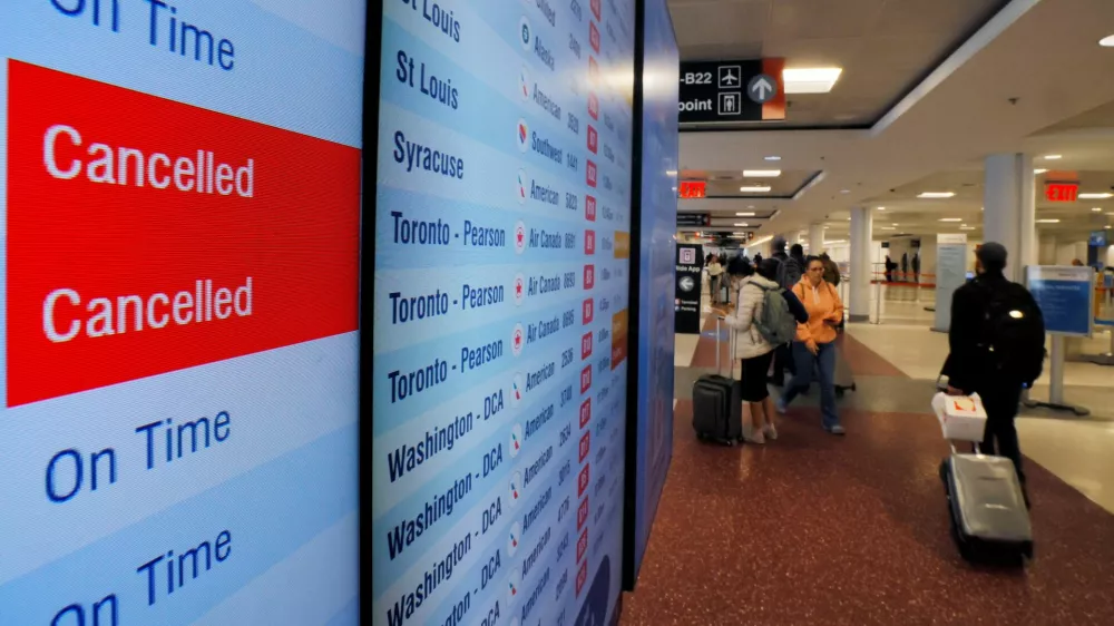 A board shows two cancelled American Airlines flights and three on time, as airlines cancelled flights at 40 major airports after the government imposed an unprecedented cut to air travel, citing air traffic control safety concerns because of a record-setting government shutdown, at Logan International Airport in Boston, Massachusetts, U.S., November 7, 2025.  REUTERS/Brian Snyder