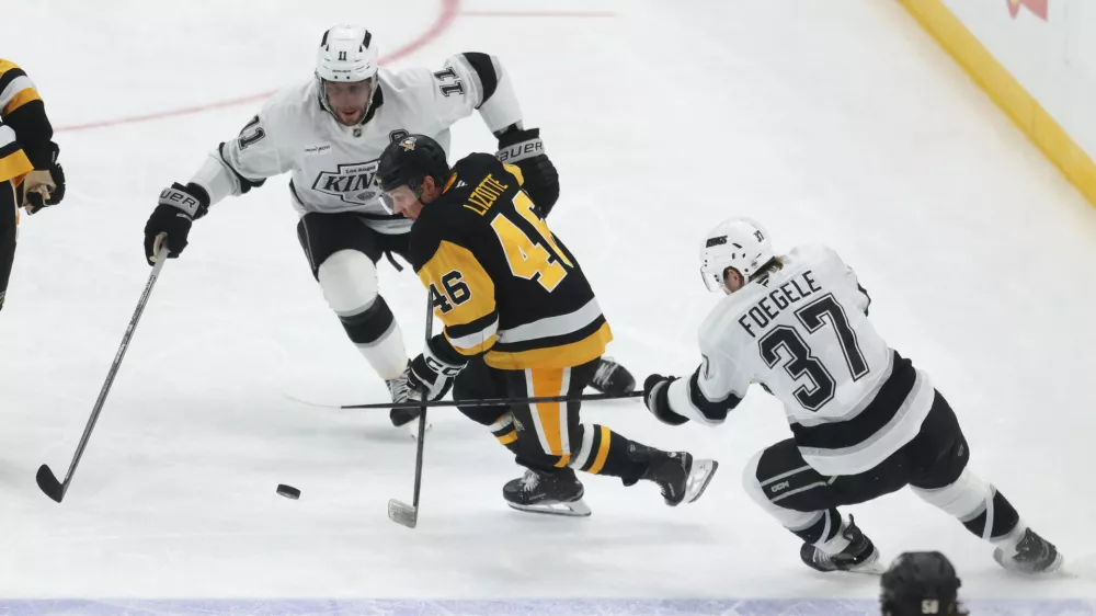 Nov 9, 2025; Pittsburgh, Pennsylvania, USA; Los Angeles Kings center Anze Kopitar (11) and left wing Warren Foegele (37) defend Pittsburgh Penguins center Blake Lizotte (46) during the third period at PPG Paints Arena. Mandatory Credit: Charles LeClaire-Imagn Images
