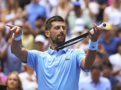 Novak Djokovic, of Serbia, pretends to play the violin after defeating Zachary Svajda, of the United States, during the second round of the U.S. Open tennis championships, Wednesday, Aug. 27, 2025, in New York. (AP Photo/Kirsty Wigglesworth)