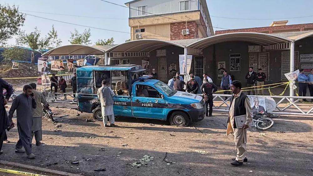 Security officials examine a damage vehicle at the site following a suicide bombing outside the gates of a district court, in Islamabad, Pakistan, Tuesday, Nov. 11, 2025. (AP Photo/Mohammad Yousuf)