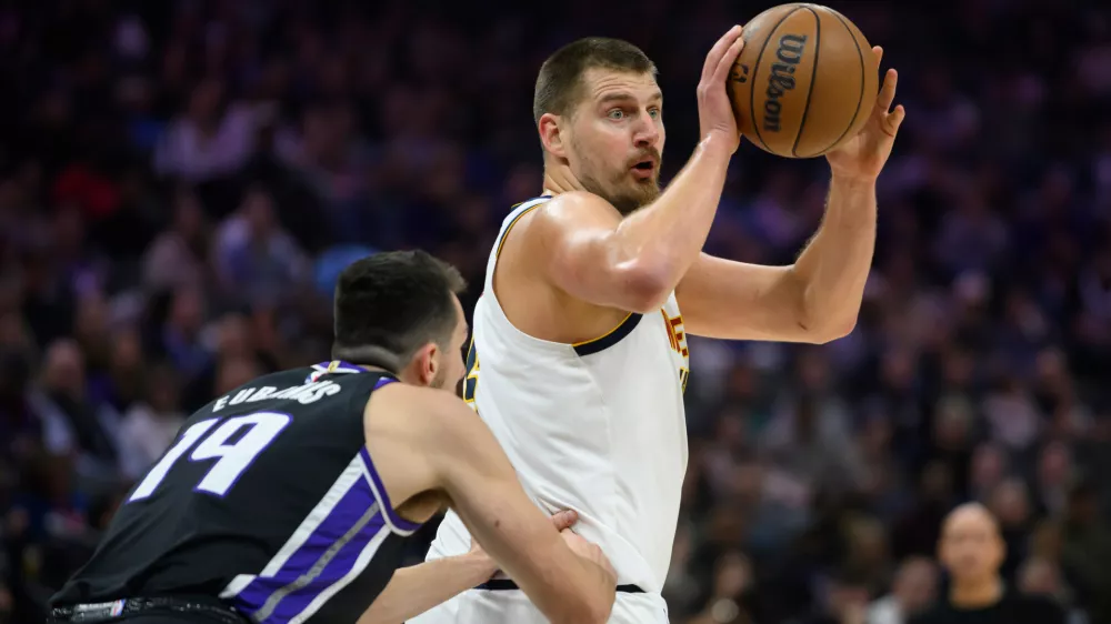 Denver Nuggets center Nikola Jokić, right, prepares to pass the ball past Sacramento Kings forward/center Drew Eubanks (19) during the first half of an NBA basketball game in Sacramento, Calif., Tuesday, Nov. 11, 2025. (AP Photo/Randall Benton)
