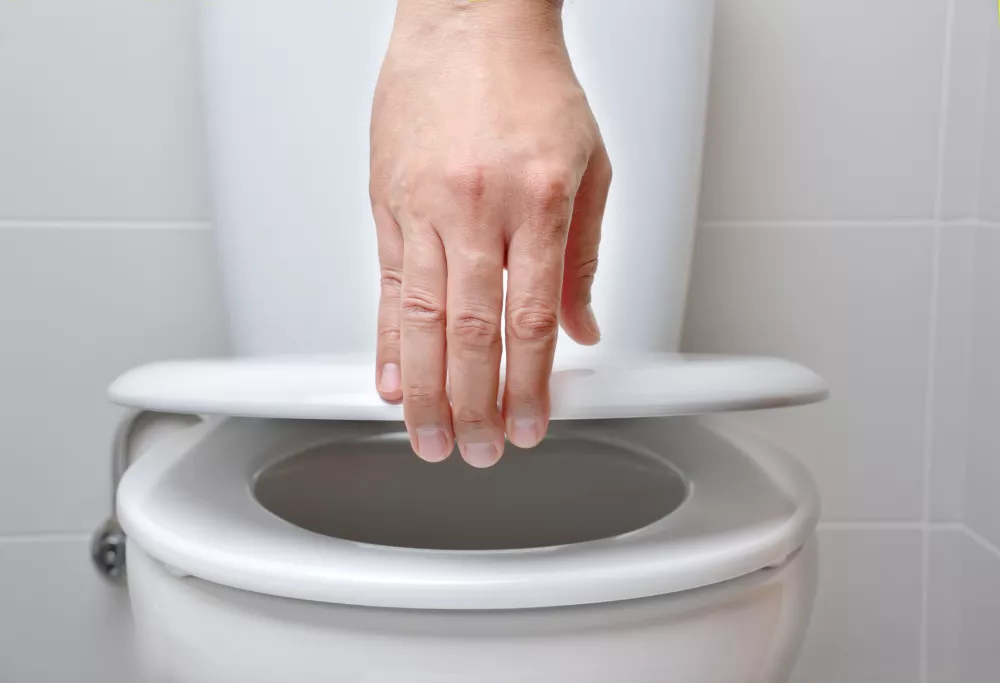 hand of a man closing the lid of a toilet / Foto: Cunaplus_m.faba