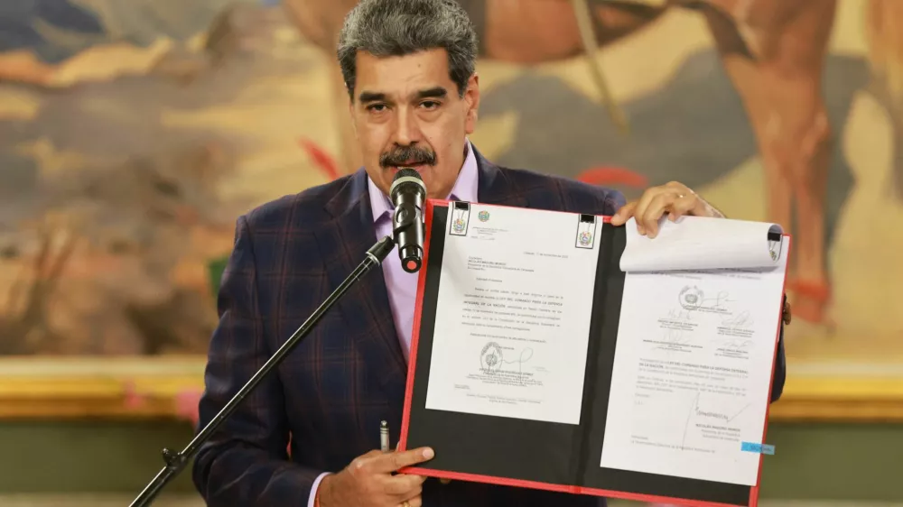Venezuela's President Nicolas Maduro holds a folder with a national defense framework approved by Venezuela's National Assembly, ordering the immediate activation of "integral defense commands" to unify civilian and military forces, according to state television, in Caracas, Venezuela, November 11, 2025. Miraflores Palace/Handout via REUTERS ATTENTION EDITORS - THIS IMAGE HAS BEEN SUPPLIED BY A THIRD PARTY