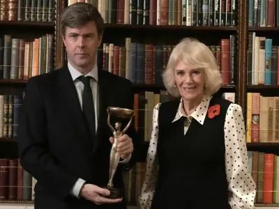 Britain's Queen Camilla poses for a photo with 2025 Booker prize winner David Szalay during a reception for shortlisted authors, judges and supporters, celebrating the Booker Prize 2025 and the newly announced Children's Booker Prize, at Clarence House in London, Britain, November 11, 2025. Stefan Rousseau/Pool via REUTERS