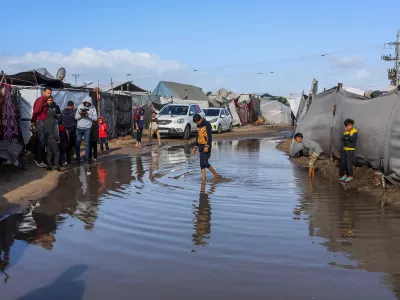 15 November 2025, Palestinian Territories, Khan Yunis: Children walk through the rainwater between their tents, as Palestinians suffer from the bitter cold and heavy rains that inundate their tents in the Al-Attar area of ··Mawasi, west of Khan Younis in the southern Gaza Strip. Photo: Abed Rahim Khatib./dpa