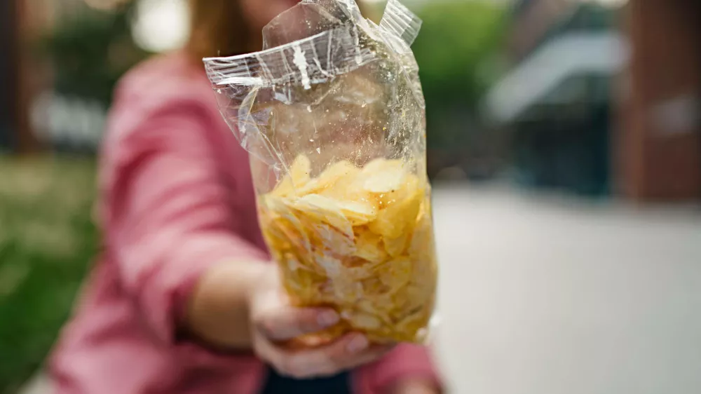 Curvy woman offering from bag of chips. Curvy woman offering from bag of potato chips. model releasedNo Use Switzerland. No Use Germany. No Use Japan. No Use Austria