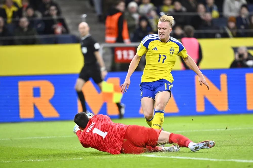 Slovenia's goalkeeper Igor Vekic, left, blocks a shot by Sweden's Isac Lidberg during the 2026 World Cup qualifier group B soccer match between Sweden and Slovenia, in Stockholm, Tuesday, Nov. 18, 2025. (Pontus Lundahl/TT News Agency via AP)