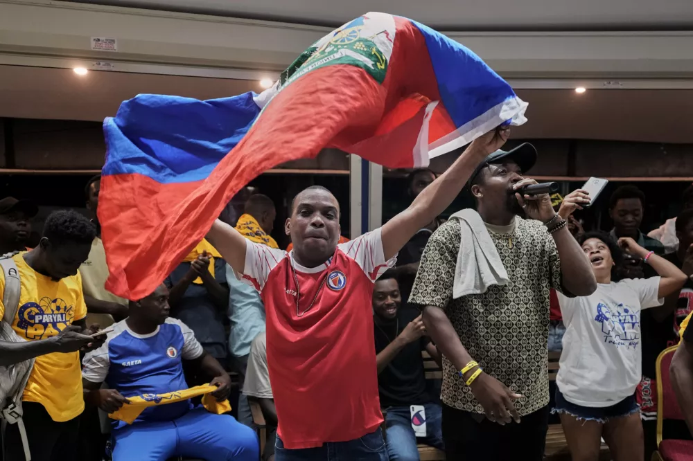 Fans watching a 2026 FIFA World Cup qualifying match between Haiti and Nicaragua celebrate Haiti's first goal, in Port-au-Prince, Haiti, Tuesday, Nov. 18, 2025. (AP Photo/Odelyn Joseph)