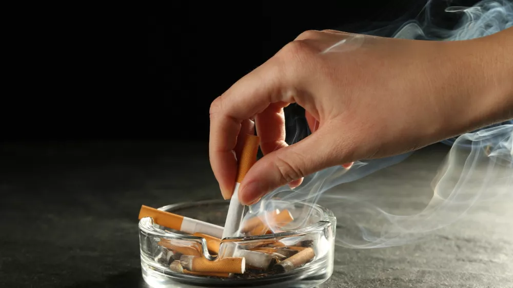 Woman extinguishing cigarette in glass ashtray