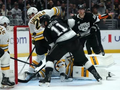 Nov 21, 2025; Los Angeles, California, USA; Los Angeles Kings center Anze Kopitar (11) fighst for the puck against Boston Bruins defenseman Hampus Lindholm (27) during the second period at Crypto.com Arena. Mandatory Credit: Kiyoshi Mio-Imagn Images