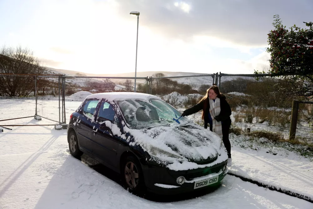A woman clears snow from her car in the village of Cargan, Northern Ireland, November 20, 2025. REUTERS/Cathal McNaughton