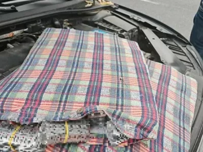 Moški je več paketov tablet skril pod pokrov motorja. 