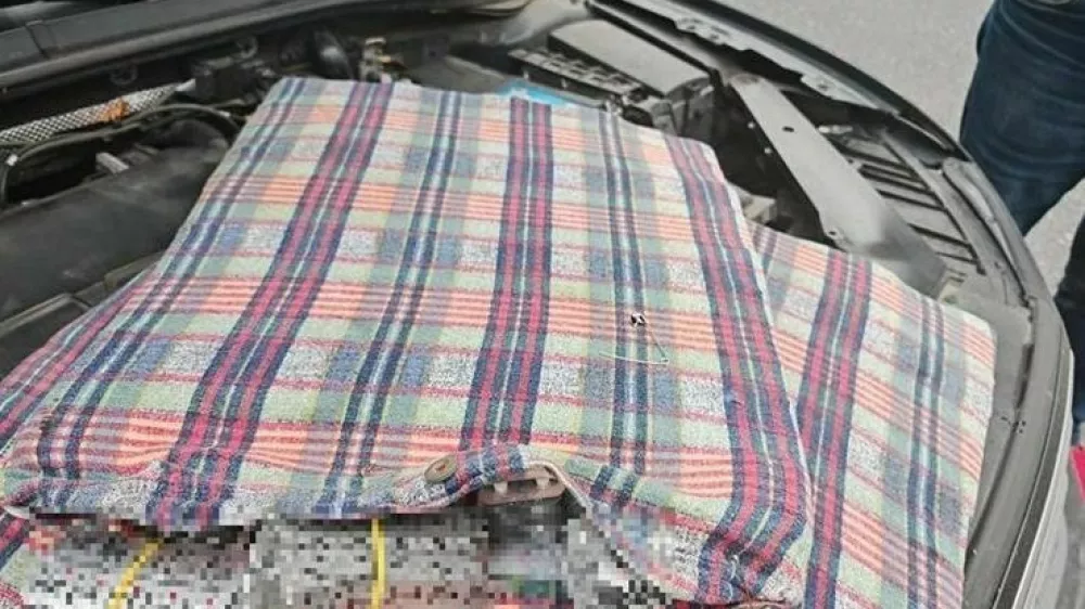 Moški je več paketov tablet skril pod pokrov motorja. 