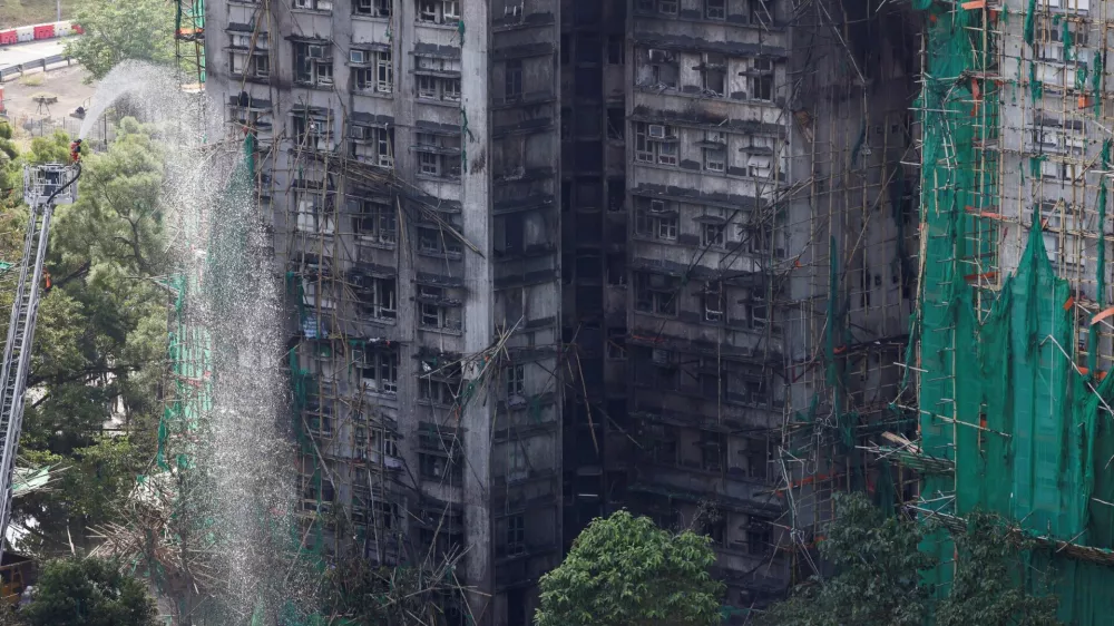 A firefighter works in front of the multiple charred buildings of Wang Fuk Court complex following a deadly fire, in Tai Po, Hong Kong, China, November 28, 2025. REUTERS/Tyrone Siu housing estate,