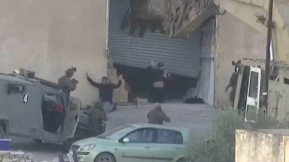 This image taken from video by Palestine TV shows two Palestinian men kneeling on the ground to Israeli forces shortly before they were shot dead during a military operation in Jenin, West Bank, on Thursday, Nov. 27, 2025. (Palestine TV via AP)