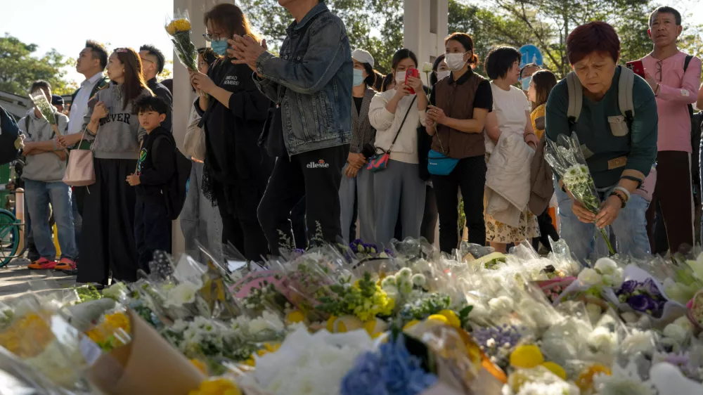 People pray and lay flowers near the site of the deadly Wednesday fire at Wang Fuk Court, a residential estate in the Tai Po district of Hong Kong's New Territories on Saturday, Nov. 29, 2025. (AP Photo/Ng Han Guan)