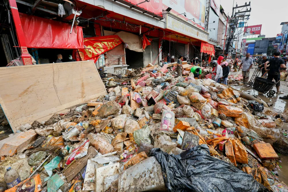Peoples walk near goods damaged from floods in Songkhla province, southern Thailand, Saturday, Nov. 29, 2025. (AP Photo/Sarot Meksophawannakul)