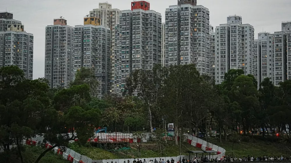 People queue to place flowers at a makeshift memorial near Wang Fuk Court housing estate to pay tribute to victims of the deadly fire at the Wang Fuk Court housing complex, in Tai Po, Hong Kong, China, November 30, 2025. REUTERS/Lam Yik