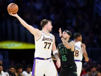 Los Angeles Lakers guard Luka Doncic (77) holds the ball against New Orleans Pelicans guard Jose Alvarado (15) as Los Angeles Lakers forward Rui Hachimura, right, runs during the first half of an NBA basketball game, Sunday, Nov. 30, 2025, in Los Angeles. (AP Photo/Jessie Alcheh)