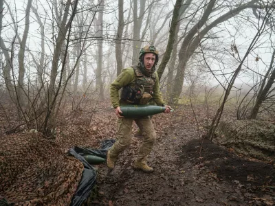 A Ukrainian serviceman of the Da Vinci Wolves Battalion carries an artillery shell before firing toward Russian positions at the front line in eastern Ukraine, on Friday, Nov. 28, 2025. (AP Photo/Evgeniy Maloletka)