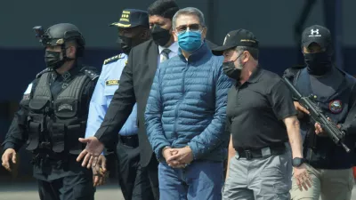 FILE PHOTO: Honduras former President Juan Orlando Hernandez is escorted by authorities as he walks towards a plane of the U.S. Drug Enforcement Administration (DEA) for his extradition to the United States, to face a trial on drug trafficking and arms possession charges, at the Hernan Acosta Mejia Air Force base in Tegucigalpa, Honduras April 21, 2022. REUTERS/Fredy Rodriguez/File Photo