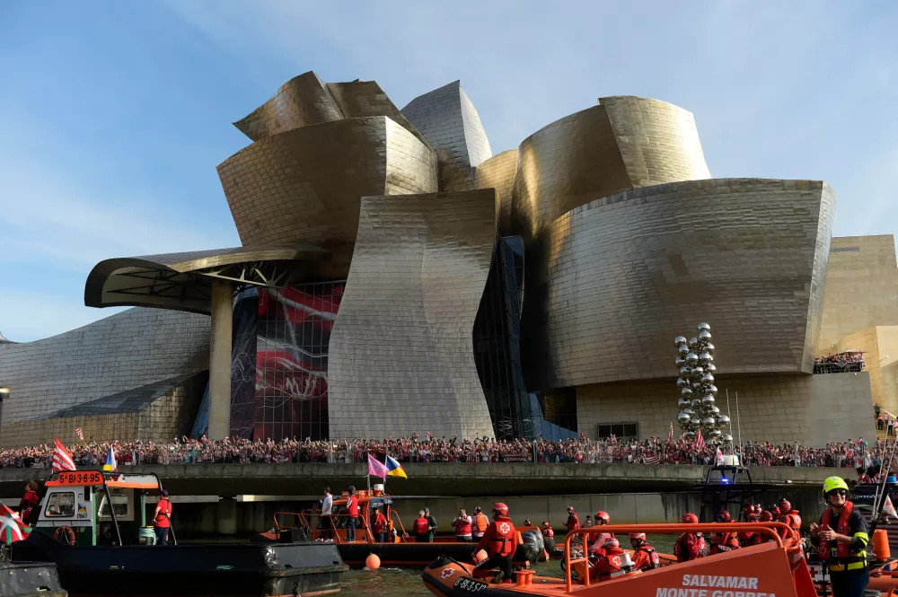 FILE - Athletic Bilbao fans wait in front of the Guggenheim museum as support boats pass before team celebrations on the Nervion Estuary in Bilbao, Spain, Thursday, April 11, 2024. (AP Photo/Alvaro Barrientos, File)