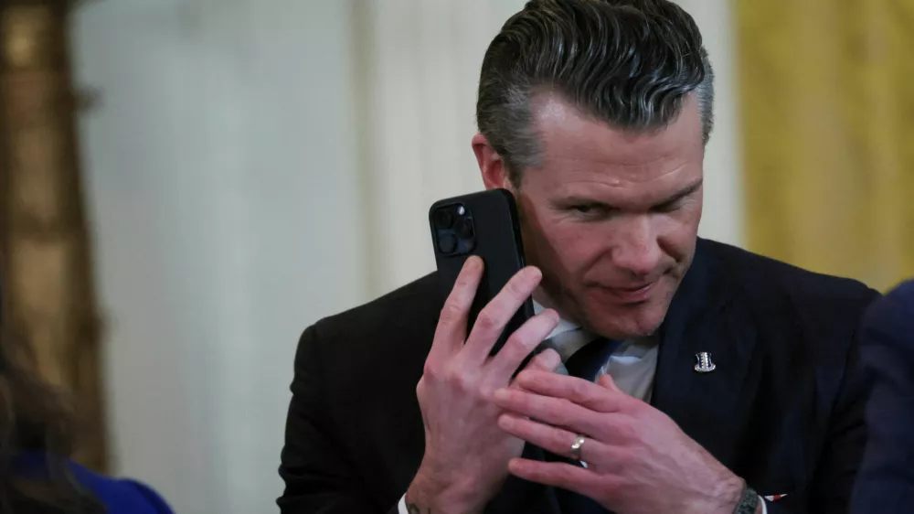 FILE PHOTO: U.S. Defense Secretary Pete Hegseth uses a phone as he attends a joint press conference of U.S. President Donald Trump and Israeli Prime Minister Benjamin Netanyahu in the East Room at the White House in Washington, U.S., February 4, 2025. REUTERS/Leah Millis/File Photo