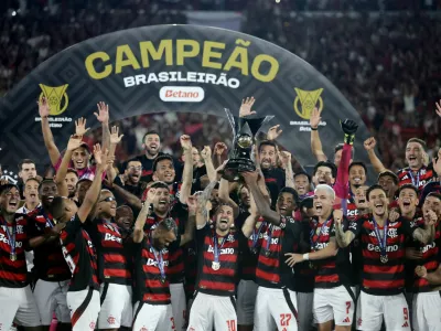 Soccer Football - Brasileiro Championship - Flamengo v Ceara - Estadio Maracana, Rio de Janeiro, Brazil - December 3, 2025 Flamengo's Giorgian de Arrascaeta and Bruno Henrique lift the trophy as they celebrate with teammates after winning the Brasileiro Championship REUTERS/Ricardo Moraes